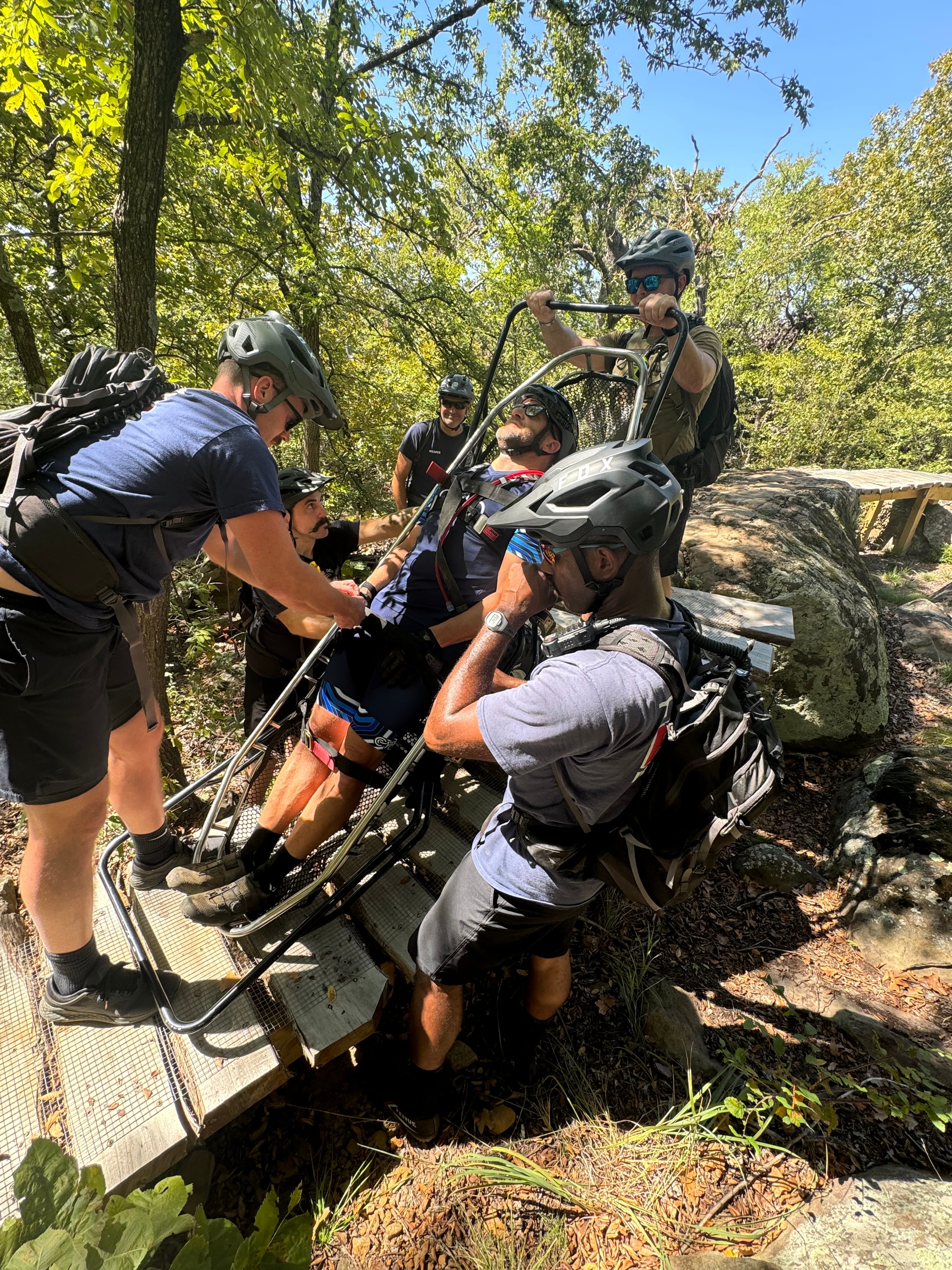 Fire Bike team conducting wilderness rescue training exercise, carrying a stretcher through a forest trail